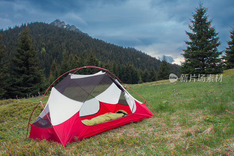 睡袋在敞开式的帐篷内，身上没有雨蝇，在山坳的草丛中清晨。背景Velky Rozsutec。马拉法特拉山脉，斯洛伐克。